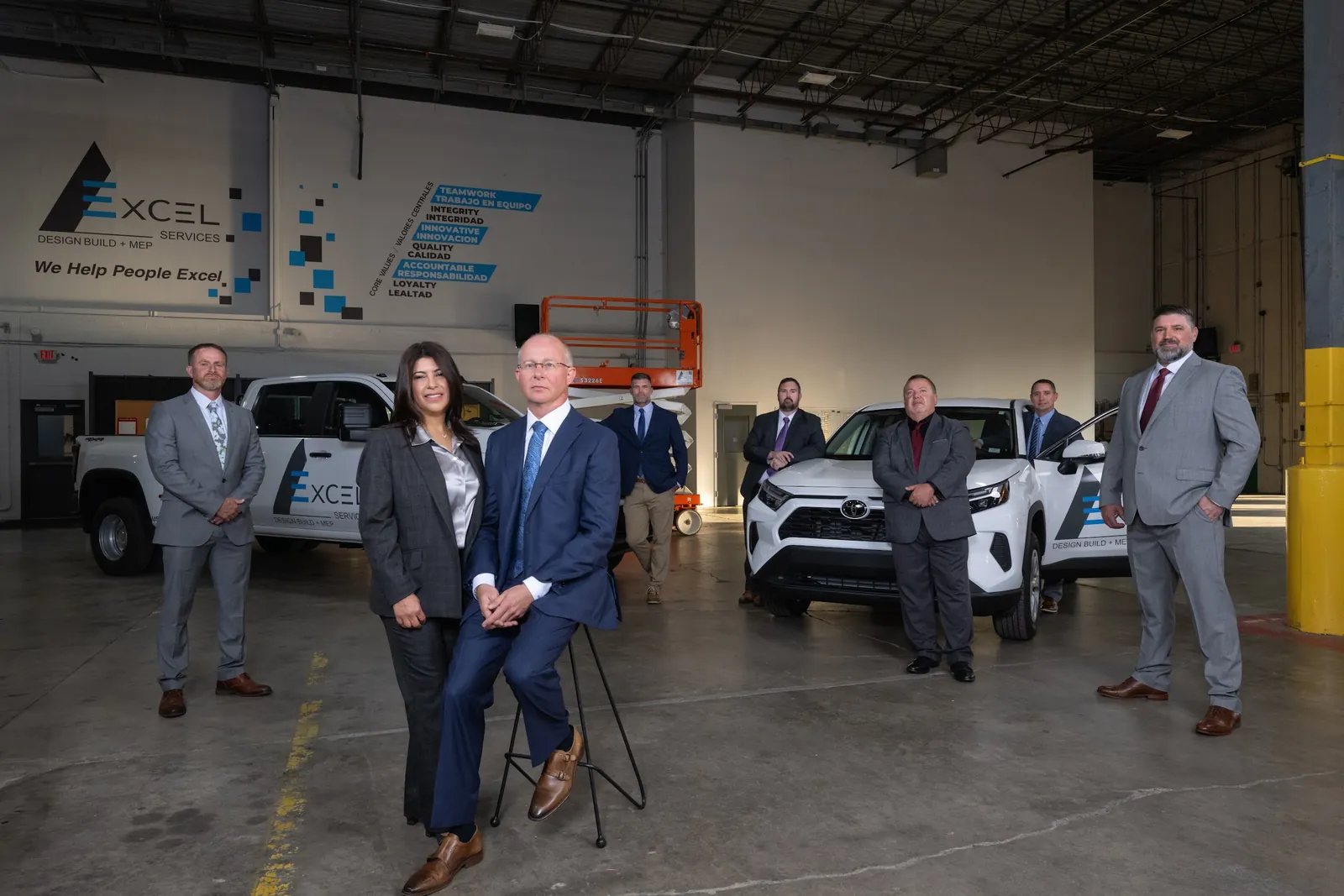 Company leadership team standing in their fleet warehouse beside branded trucks