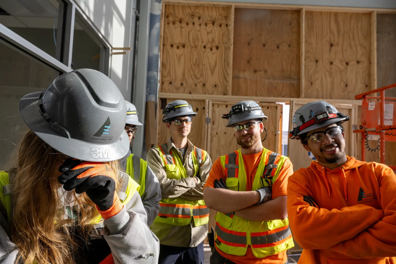 Construction crew in hard hats and safety vests smiling on site