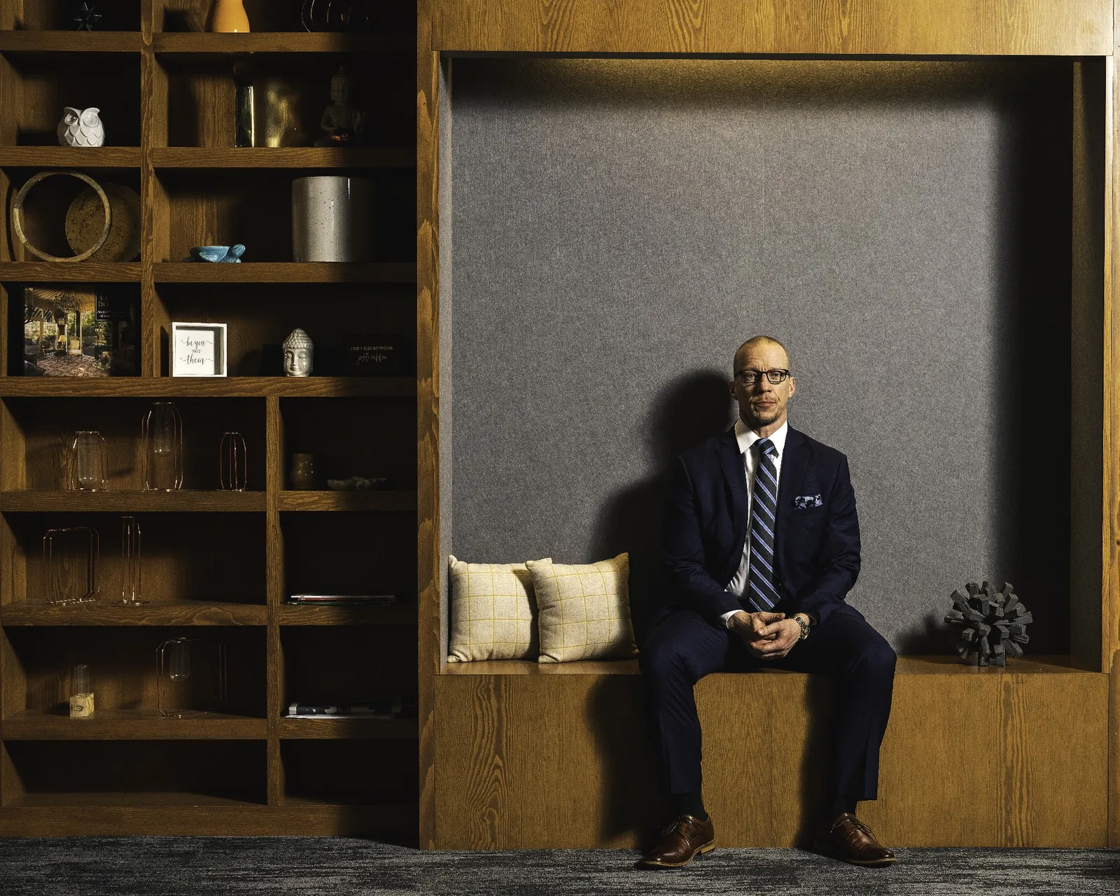 Executive seated in a lit wooden alcove beside office shelving