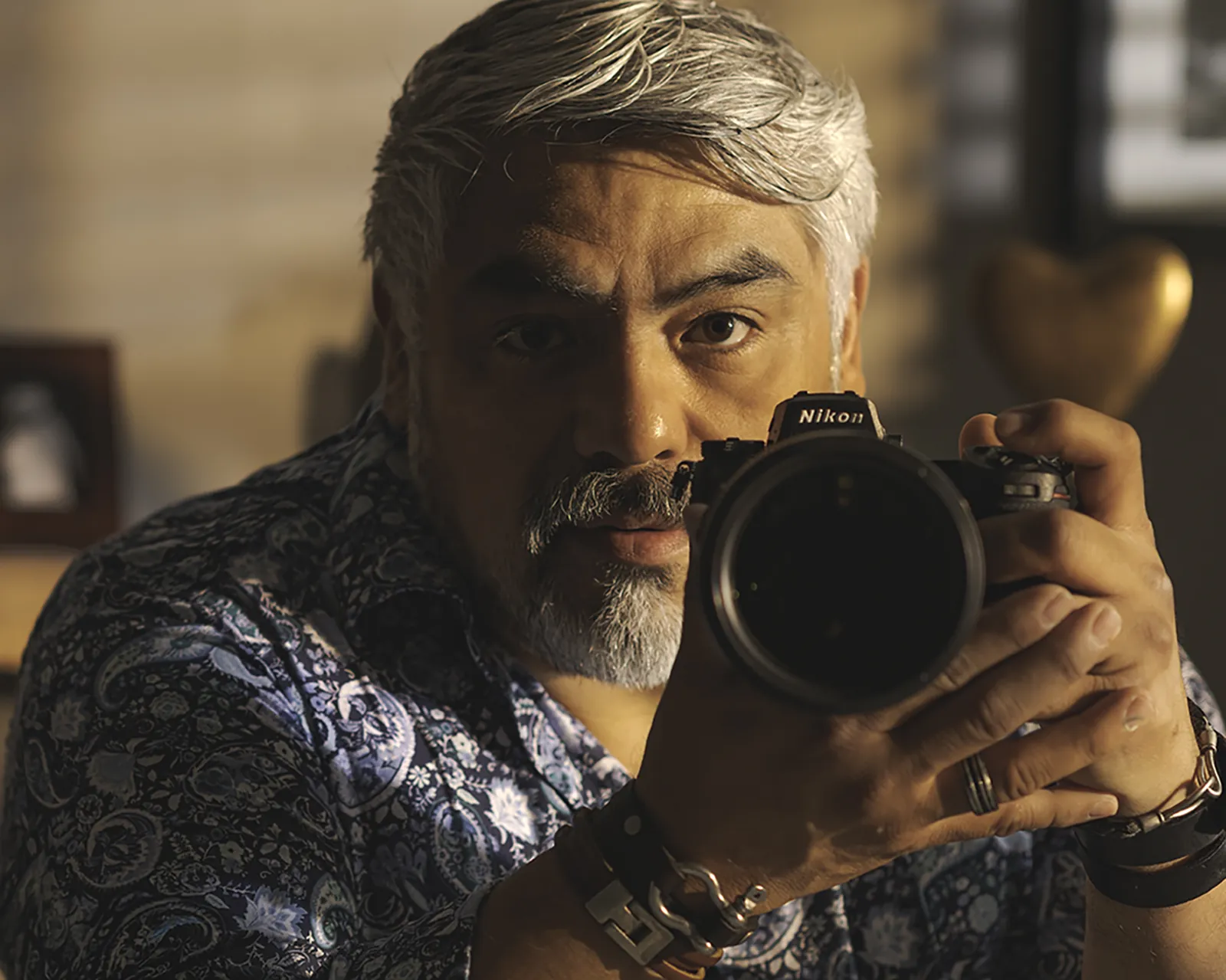 Guillermo A. Sollano holding his Nikon camera in warm window light