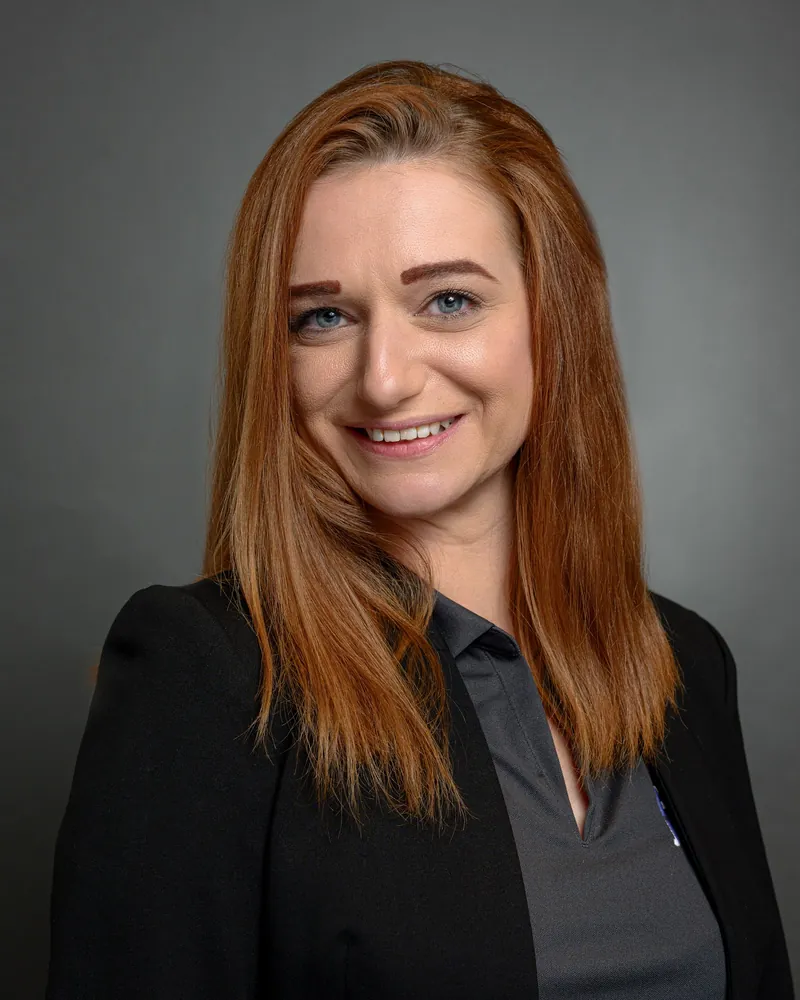 Executive headshot of a woman with long red hair on a grey backdrop