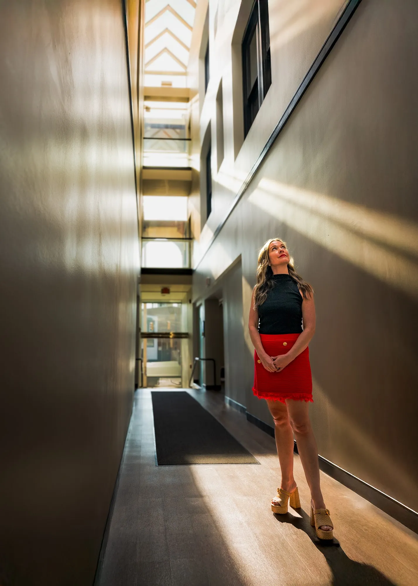 Professional standing in a sunlit office corridor