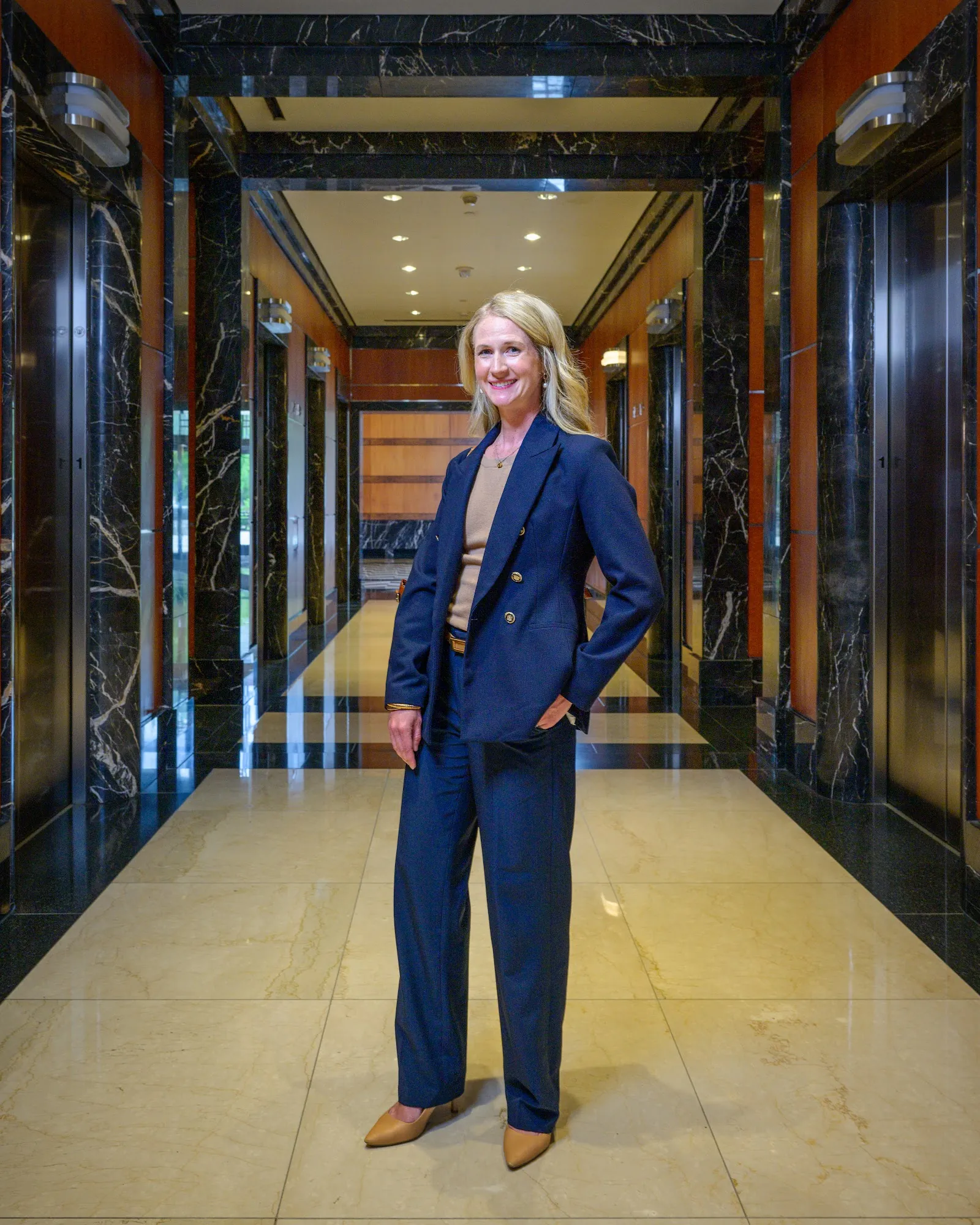 Executive in a navy suit standing in a marble office lobby